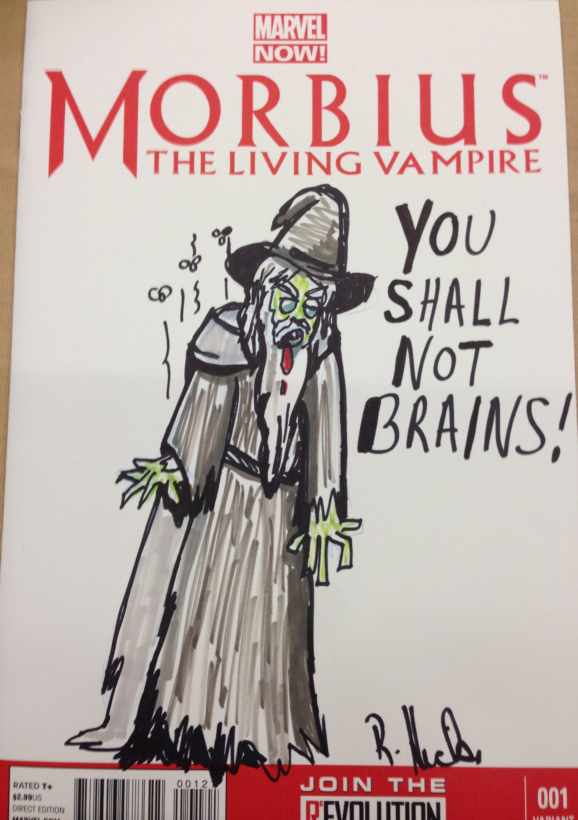 Photo of a sketch by Rebecca Hicks of zombie Gandalf saying “YOU SHALL NOT BRAINS!” Sharpie on a Morbius the Living Vampire sketch cover.