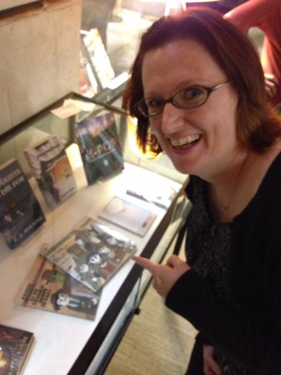 Photo of Rebecca Hicks posing with The Green, the Bleh, and the Fuzzy at the San Diego Main Library