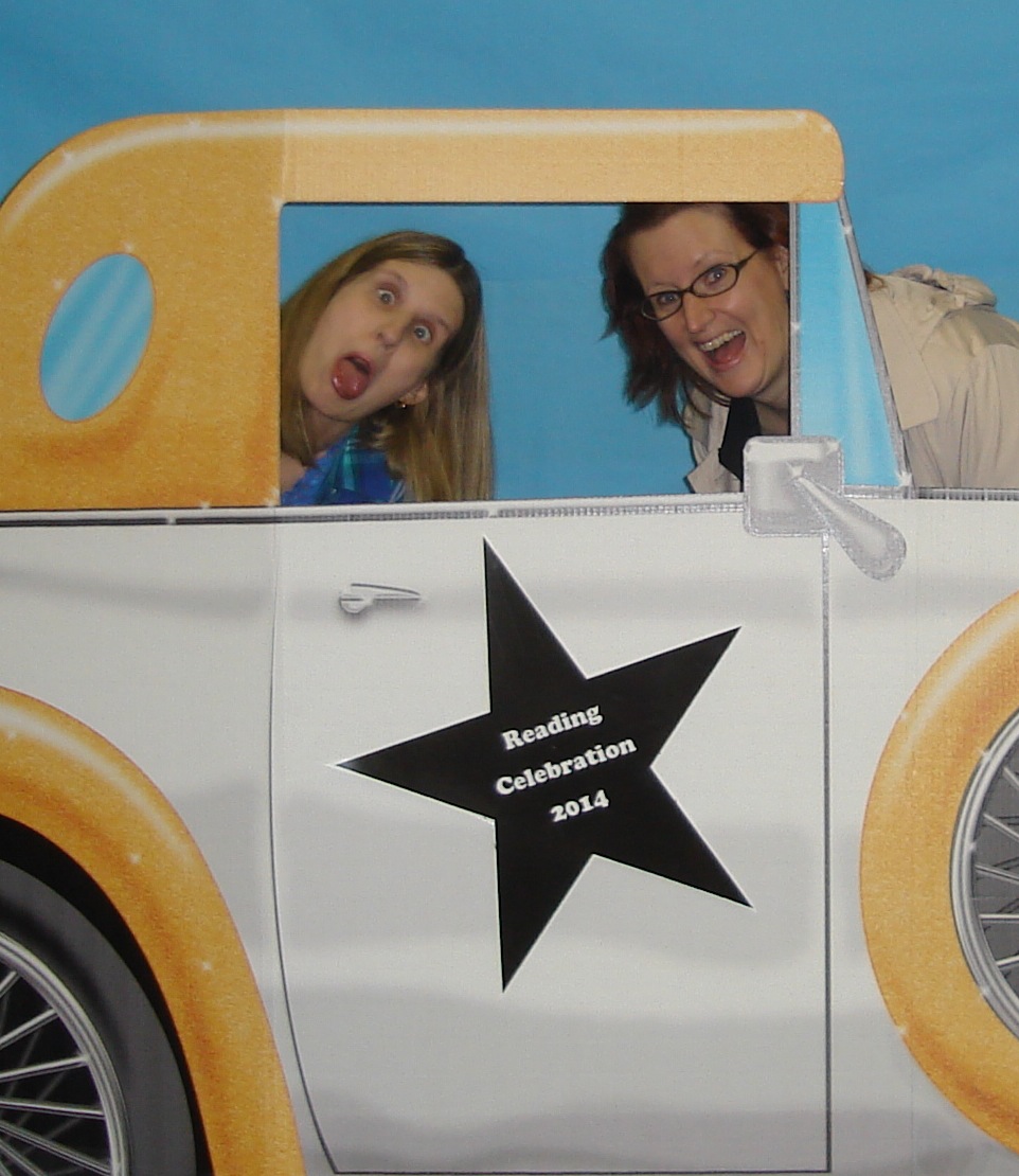 Photo of Crystal Neal and Rebecca Hicks posing behind a cardboard cutout of a car