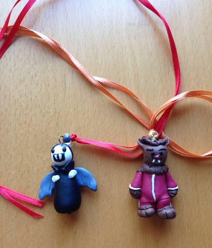 Photo of a hand-sclupted Little Vampire necklace, and a hand-sculpted Wolfie necklace