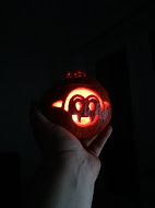 Photo of a miniature pumpkin carved as a Little Vampire jack o' lantern, brightly lit