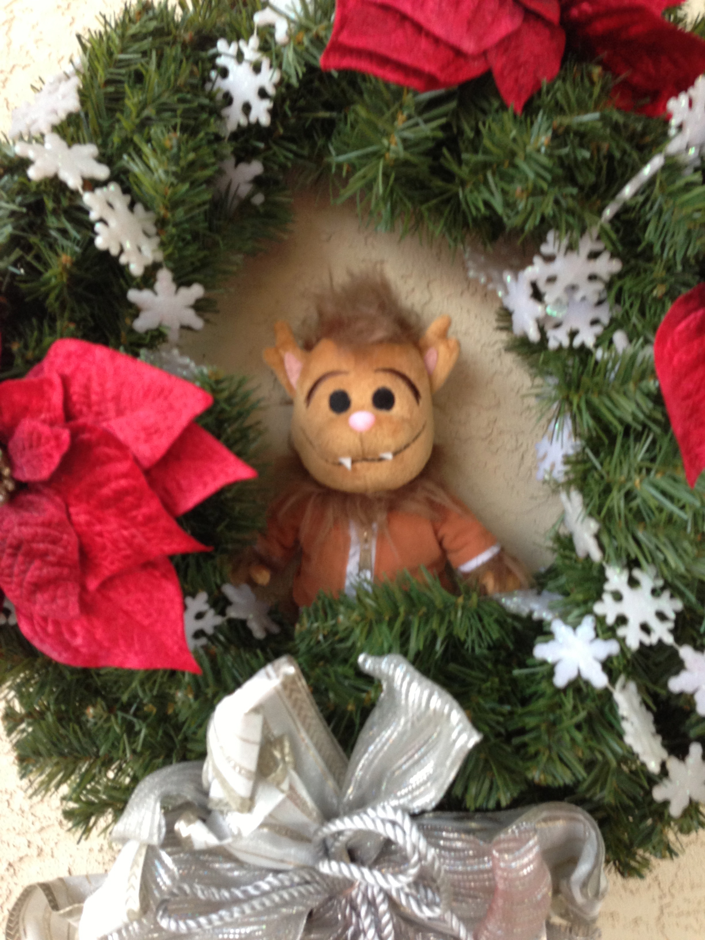 Photo of Wolfie plush toy in the center of a Christmas wreath