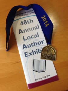 Photo of a program booklet for the San Diego Library’s 48th Annual Local Author Exhibit and a library medal