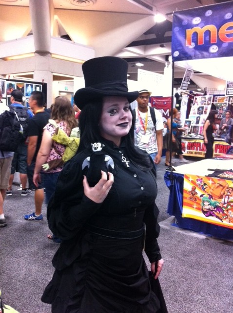 Woman wearing Death cosplay from the Sandman comic and posing with a Little Vampires plush toy