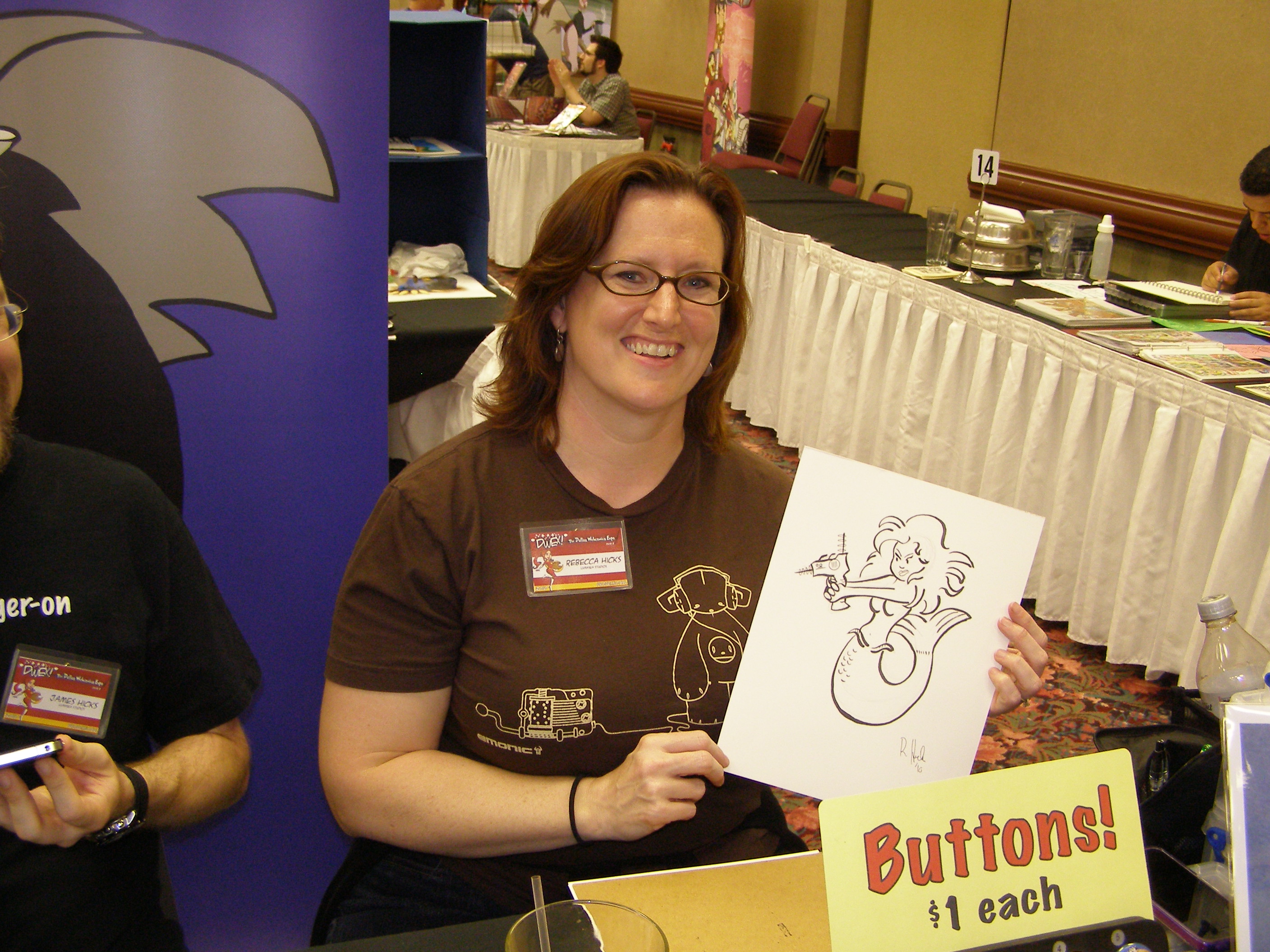 Rebeca Hicks holding a sketch of a mermaid holding a ray gun