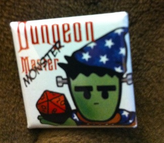 Square badge pin depicting Frank holding a D20 and wearing a wizard hat. The text reads “Dungeon Master” with the word “master” overprinted by the word “monster.
