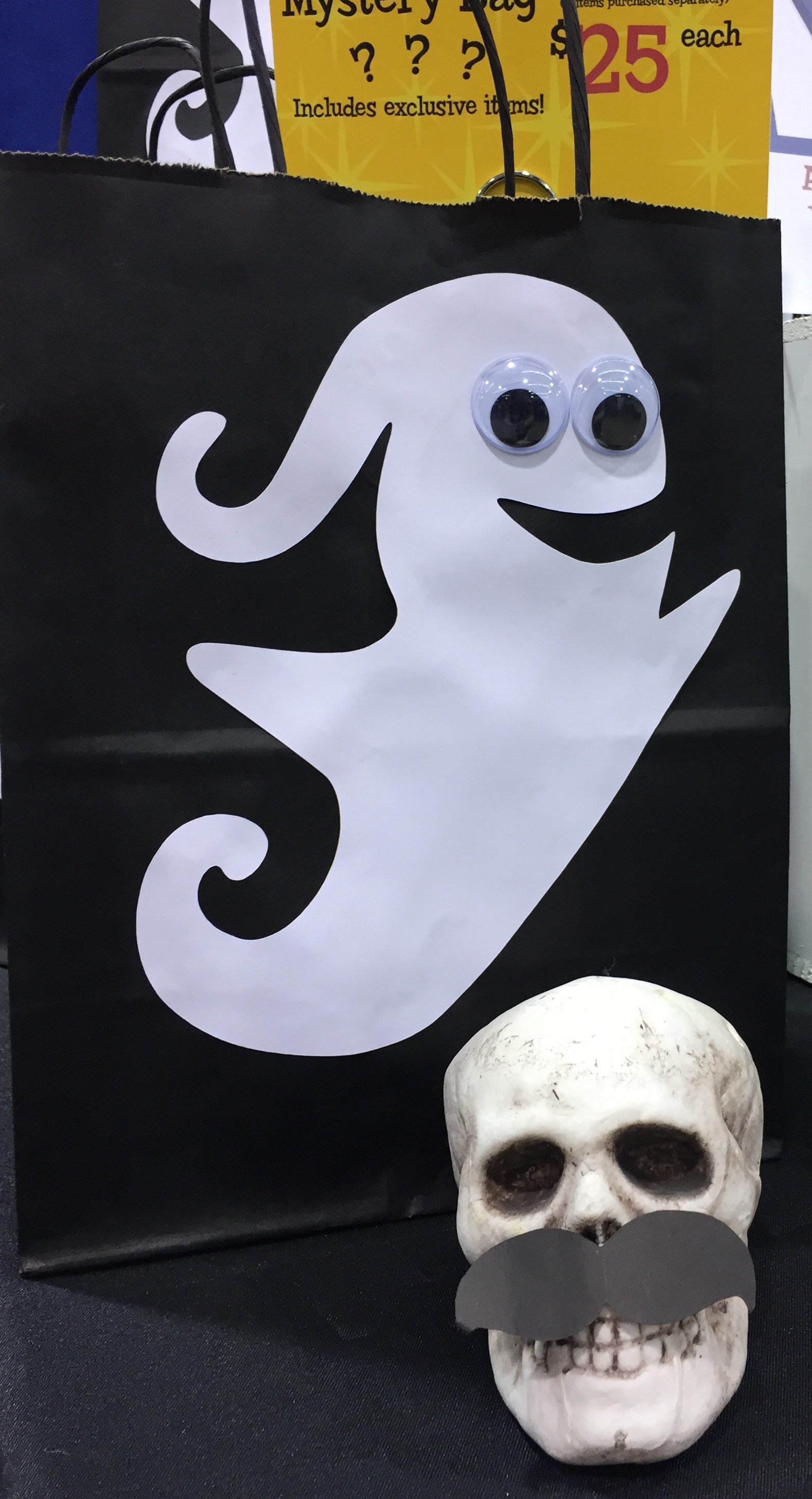 Photo of Scott the Skull posing in front a mystery bag decorated with a googly-eyed ghost