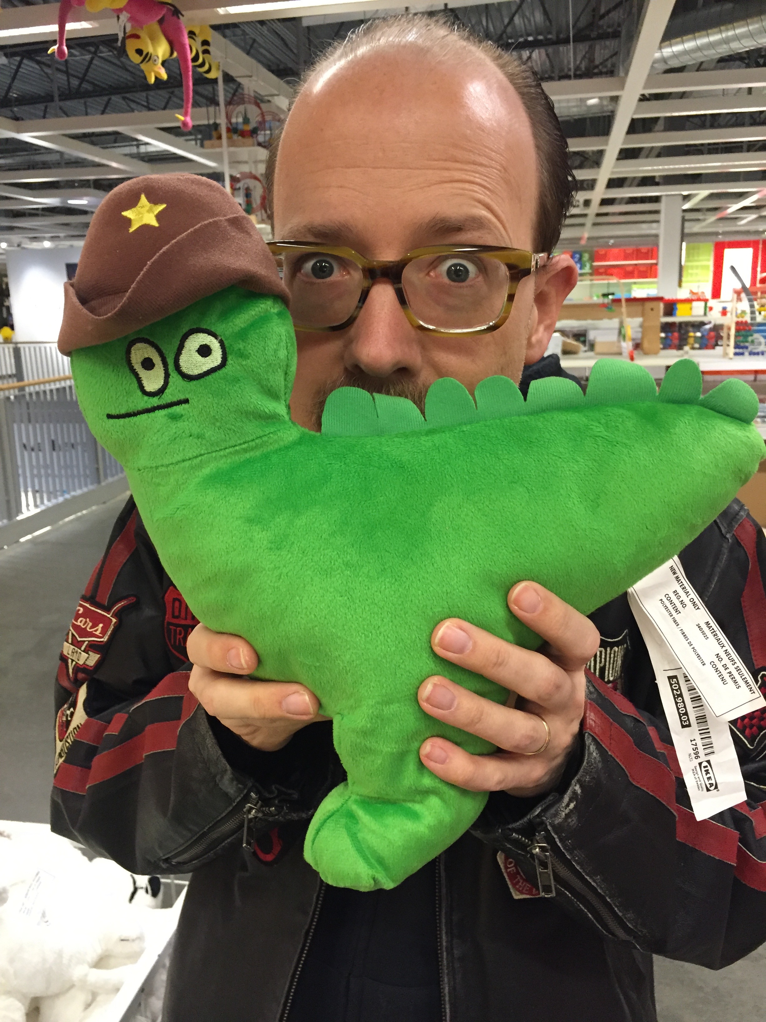 Photo of James Hicks posing with a green dinosaur plush toy