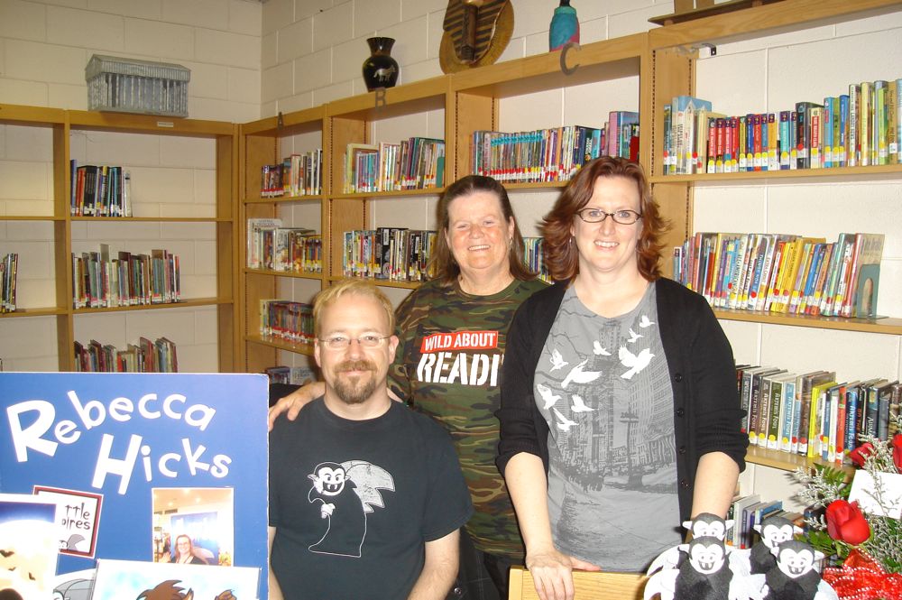 Rebecca Hicks posing with her husband and her mother behind her table to the Powell County Reading Celebration 2011