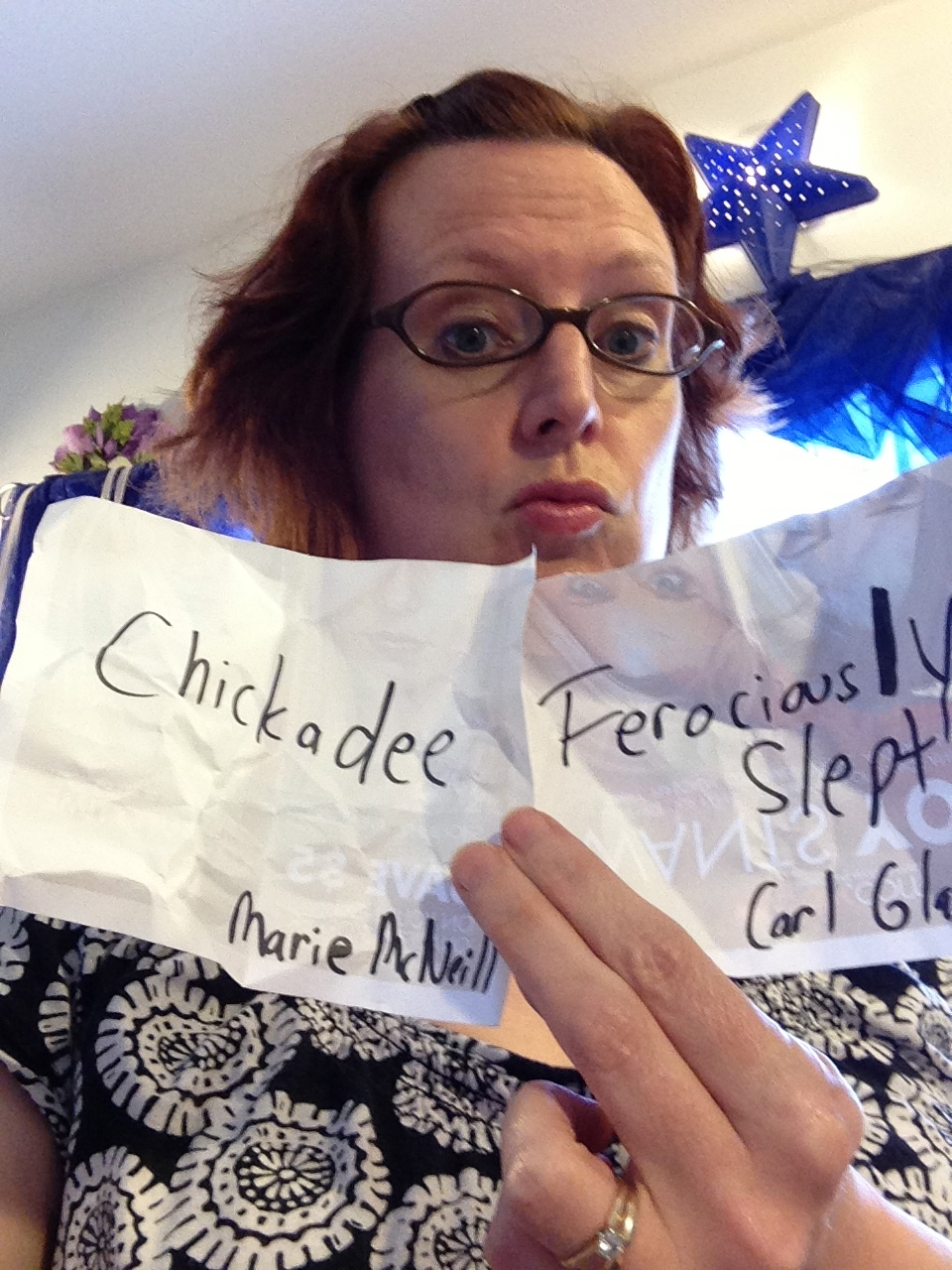 Photo of Rebecca Hicks holding pieces of paper reading “Chickadee” and “Ferociously Slept”