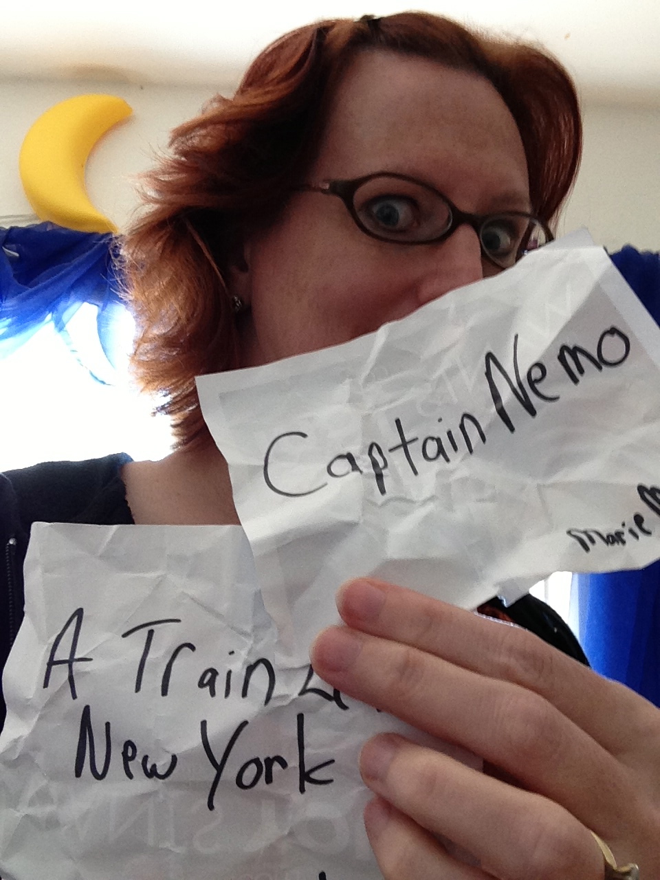 Photo of Rebecca Hicks holding pieces of paper reading “Captain Nemo” and “A Train Leaves New ork”