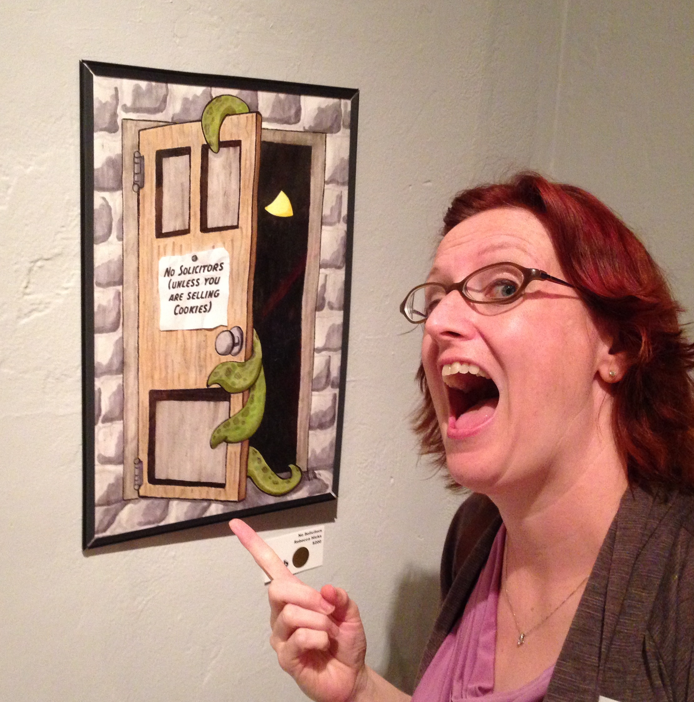 Photo of Rebecca Hicks posing in front of her newly-sold “No Solicitors” artwork