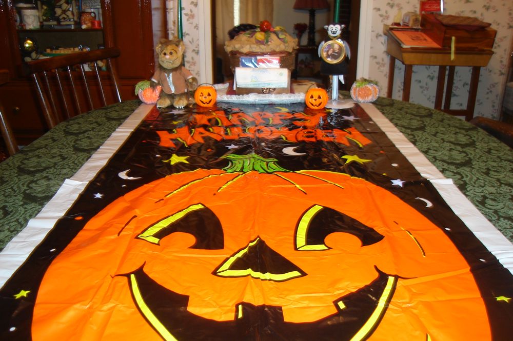 Photo of a large banner with a jack o' lantern reading “Happy Halloween” with a Wolfie and Little Vampire plush toy