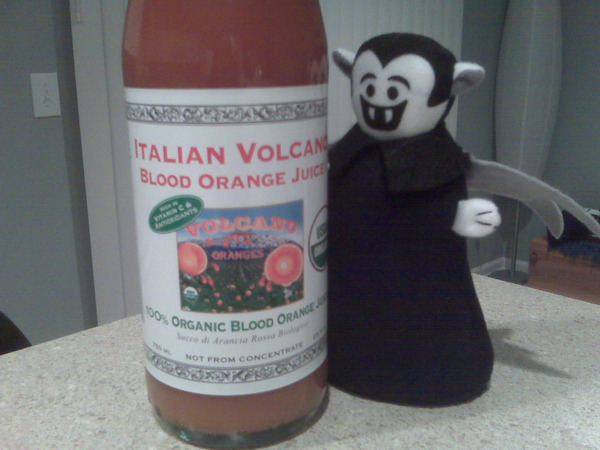 A Little Vampire posing next to a bottle of blood orange juice